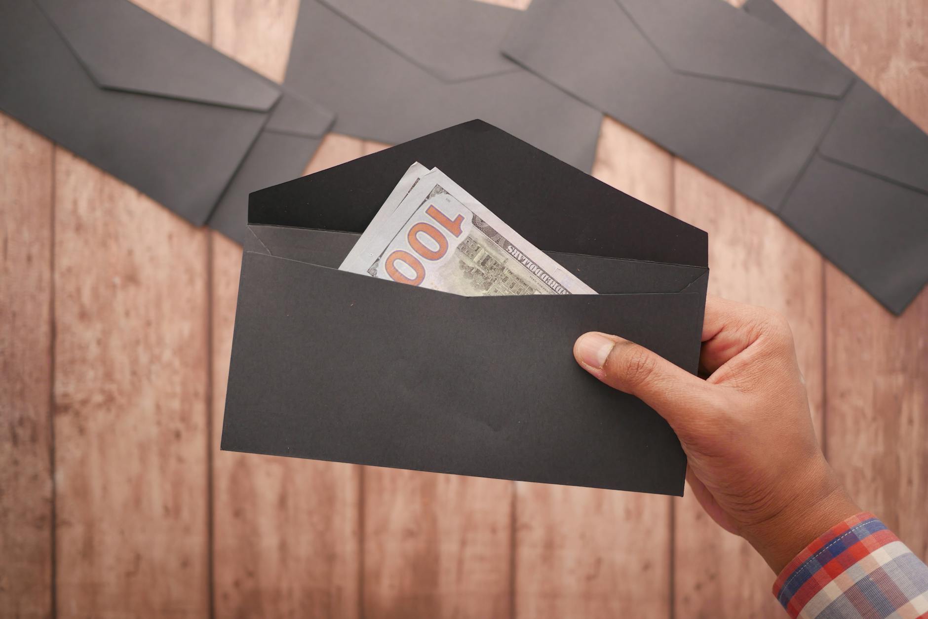 a person holding a black envelope with money